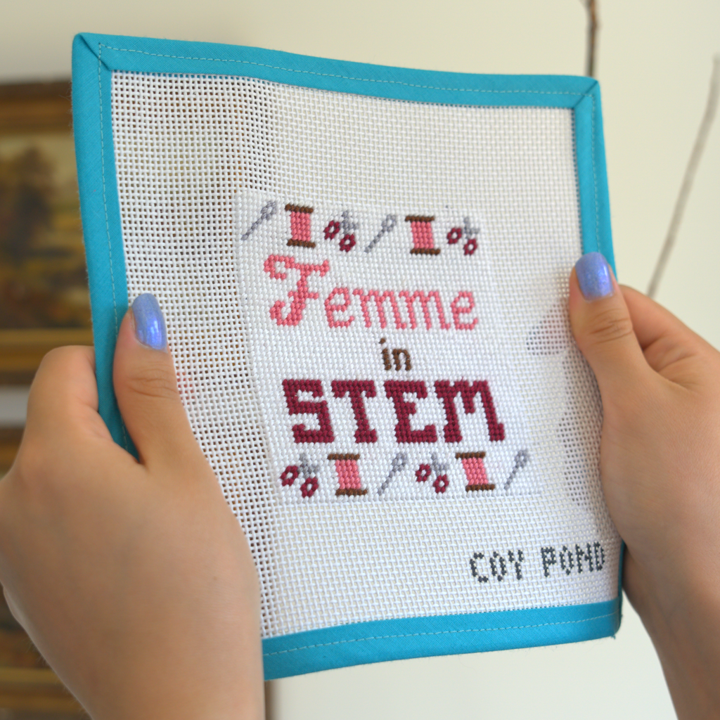 Femme in STEM Crafts needlepoint kit - completed stitched canvas showing needles, scissors and bobbins border design in pink and burgundy