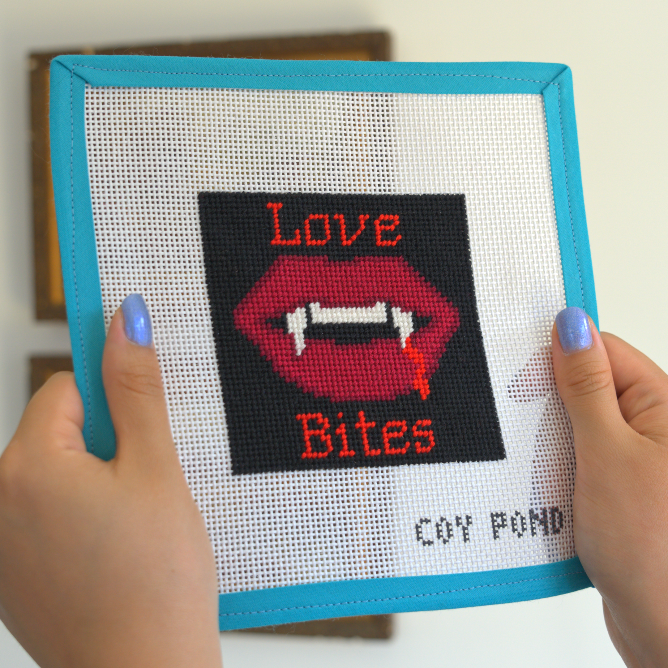 Romantasy Love Bites needlepoint kit - completed stitched canvas showing red lips with vampire fangs on black background